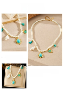 Detail of pearl necklace featuring gold-plated sea turtle, fish, and shell pendants