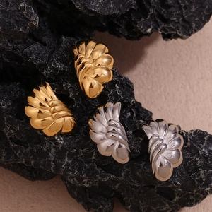 Macro detail of wave-shaped pleated fan earrings in polished gold and silver finish
