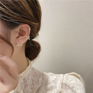 Elegant gold flower clip earrings with pearls and zircons worn by a model in lace