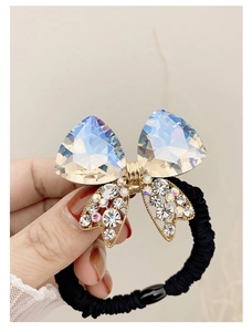 Macro shot of sparkling crystal bow hair tie with golden alloy base and black elastic band