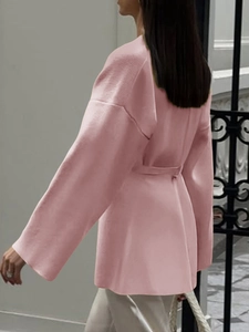 Rear view of long pink knit cardigan with belt detail and elegant loose sleeves