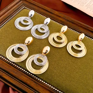 Exaggerated geometric coiled metal drop earrings in gold, silver and mixed tones