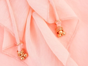 Close-up of pink midi dress fabric with luxury gold metal ring and bead details