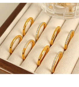 Close-up of eight gold rings with pavé diamonds in a beige velvet jewelry box
