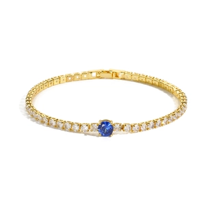 Detail of gold-plated tennis bracelet featuring a round-cut blue center stone