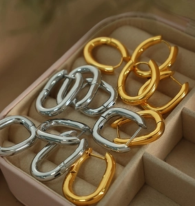 Macro view of gold and silver U-shaped hoop earrings in a minimalist jewelry box