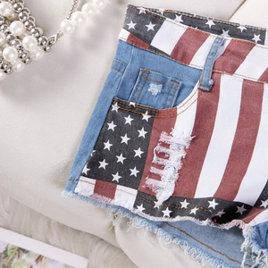Dettaglio macro degli shorts in denim con stampa bandiera USA e bordi sfrangiati