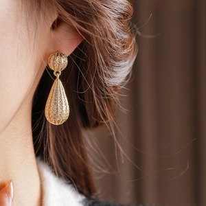 Detailopname van vintage gouden druppeloorbellen met kristallen bij een model
