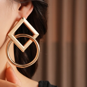 Gros plan de boucles d'oreilles dorées géométriques avec carré et cercle sur mannequin