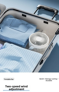 White portable desk fan stored in a suitcase highlighting travel portability and compact size