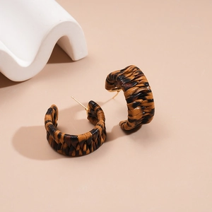 Close-up of C-shaped hoop earrings with brown leopard print woven leather texture