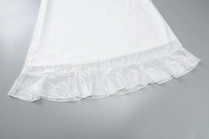 Close-up of white lace dress hem featuring intricate floral patterns and ruffled edges