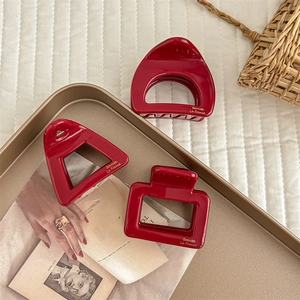 Three red acetic acid hair claws in geometric shapes on a vintage gold tray