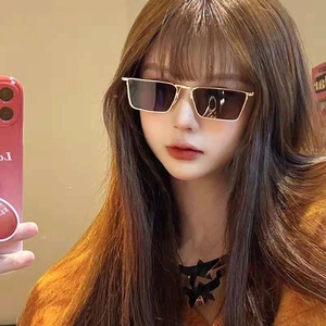 Close-up of square gold metal sunglasses with dark gradient lenses worn by model