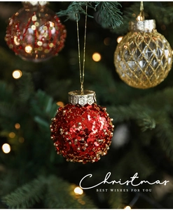 Close-up of sparkling red and gold Christmas ornaments hanging on a pine tree