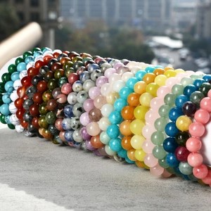 Detailed pile of 8mm colorful natural stone bead bracelets on a concrete surface