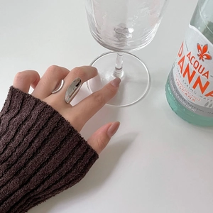 Close-up of an irregular silver open ring worn on a finger with a stylish knitted sleeve
