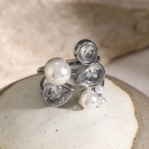 Detailed macro shot of irregular open ring with white pearls and clear zircons on ceramic
