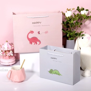 Detailansicht der rosa und grauen Papiertüten mit Dinosaurier-Motiv und Kordelgriff