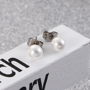 Detailed macro view of white shell pearl earrings with stainless steel posts
