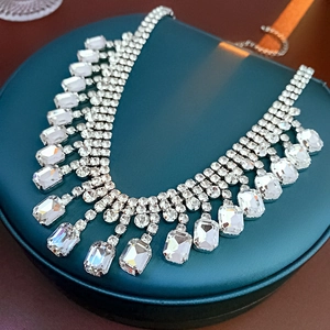 Gros plan d'un collier à franges en cristal argenté posé sur un écrin en cuir vert foncé