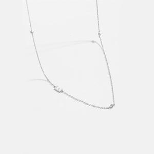 Detailed macro shot of a silver letter E necklace with crystal stone and bead detail