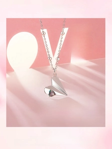 Detail of S925 sterling silver necklace with heart-shaped paper plane and rainbow gem