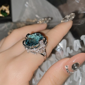 Detailed view of an oversized blue oval gemstone ring with butterfly accents and small crystals