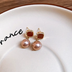 Detail of vintage square enamel earrings with artificial pink pearls on a ceramic plate