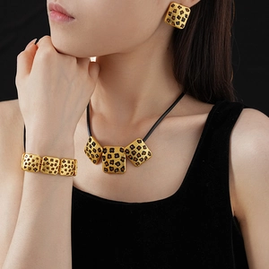 Detail of vintage gold-toned jewelry set with leopard print square patterns on model