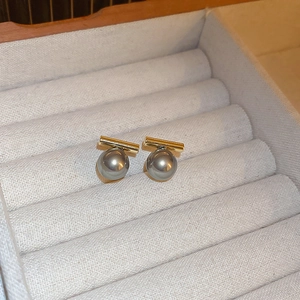 Vue macro de boucles d'oreilles minimalistes dorées avec perles grises sur du velours