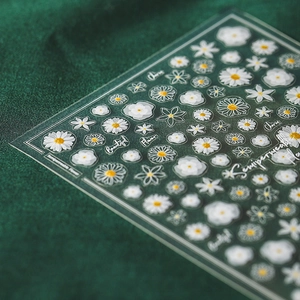 Stickers à ongles 5D fleurs blanches avec bordure dorée et texte en cursive