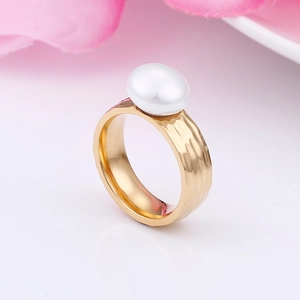 Close-up of golden hammered stainless steel ring with elegant white pearl detail