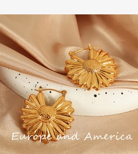Detail view of 18K gold-plated hollow flower earrings on champagne silk background