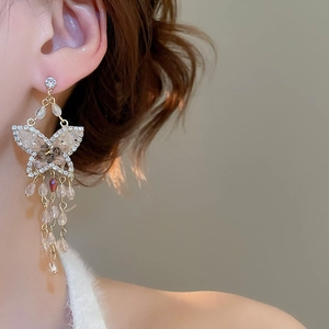 Detailed view of elegant butterfly tassel earrings with sparkling crystals on a model