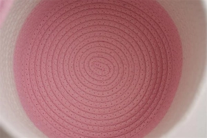 Makroaufnahme der spiralenförmigen Baumwollseil-Webdetails am rosa-weißen Korb