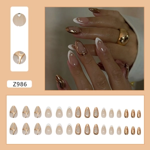 Short almond press-on nails with white French tips, gold 3D embossed accents and rhinestones