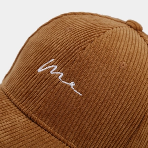 Gros plan sur la texture velours côtelé et la broderie vague sur casquette marron