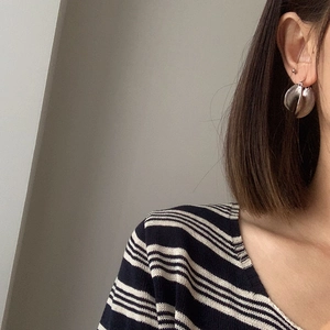Silver layered petal earrings in matte metal finish on model with striped shirt