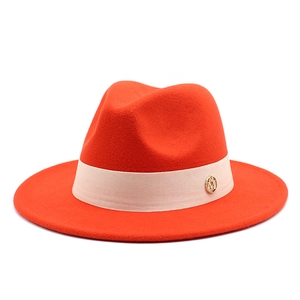 Detail of orange wool fedora featuring a wide brim, silk ribbon and golden M logo plaque
