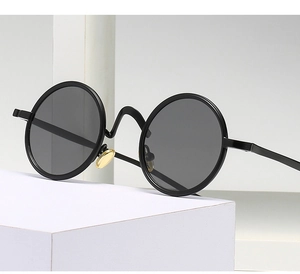 Retro-Punk-Sonnenbrille mit rundem schwarzen Rahmen und goldenen Nasenpads auf Sockel