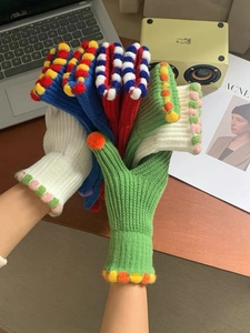 Dettaglio di guanti in maglia colorati con motivi a righe e morbidi pompon di lana