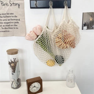 Detail of hand-woven cream cotton net bags in two sizes hanging on wooden hooks