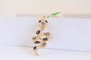 Close-up of golden snake pendant with sparkling crystals and amber rhinestones detail