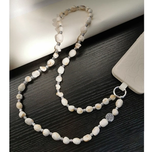 Detail of bohemian phone strap with irregular white beads and silver embossed charm pendant