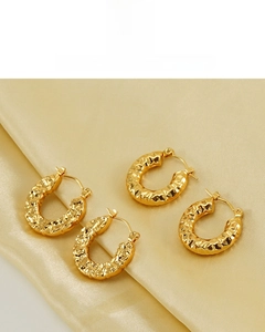 Macro detail of 18K gold plated earrings with unique hammered lava texture on silk fabric