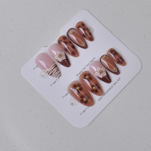Detail of semi-handmade almond press-on nails with 3D floral and leopard pattern art