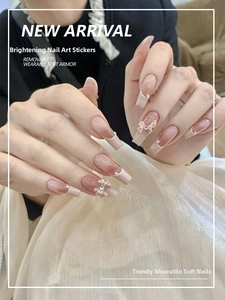 Detail of pink gradient press-on nails with bow accents and pearls on fabric