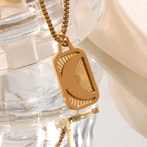 Detailed close-up of an 18K gold-plated rectangle pendant with moon and sun embossing