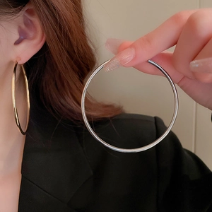 Detail of oversized circular hoop earrings in polished gold and silver metal finishes